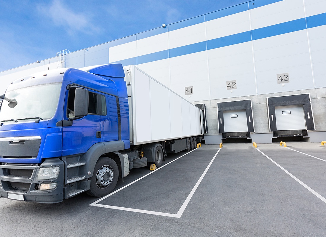 Insurance by Industry - Blue Truck With a White Trailer Parked at a Docking Area of a Warehouse